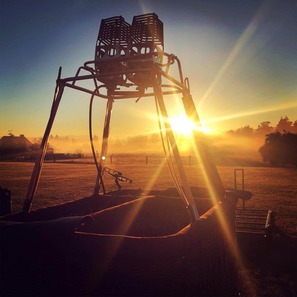 Setting up the hot air balloon basket at sunrise. Sun rays coming through the balloon burners